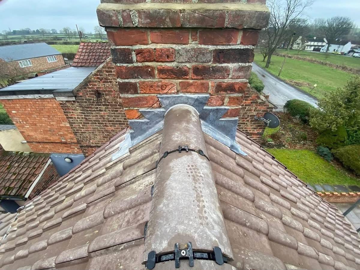 Chimney repairs and repointing in Glasgow: new leadwork and mortar around a brick chimney on a tiled roof